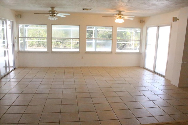 unfurnished sunroom featuring visible vents, plenty of natural light, and ceiling fan