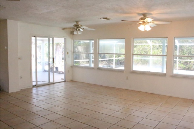 empty room featuring light tile patterned floors, visible vents, plenty of natural light, and ceiling fan