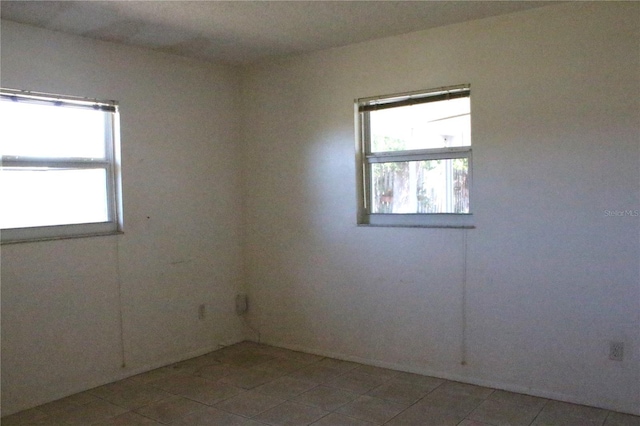 empty room with a wealth of natural light and light tile patterned flooring