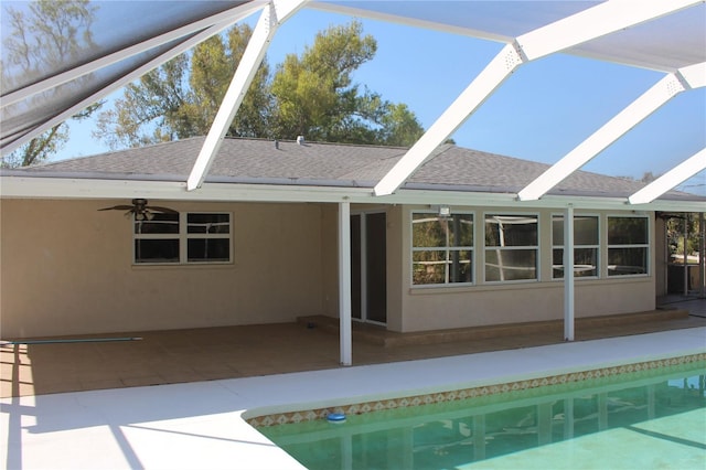 rear view of property featuring a lanai, an outdoor pool, roof with shingles, and a patio