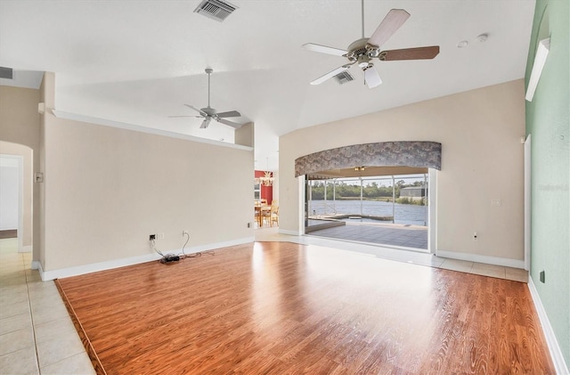 unfurnished living room featuring ceiling fan, high vaulted ceiling, wood finished floors, visible vents, and baseboards