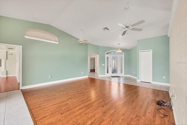 empty room featuring arched walkways, visible vents, a ceiling fan, wood finished floors, and baseboards