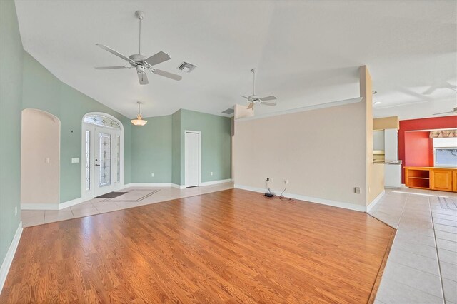 unfurnished living room with light wood-type flooring, arched walkways, visible vents, and ceiling fan