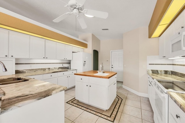 kitchen with arched walkways, wooden counters, white appliances, and a sink