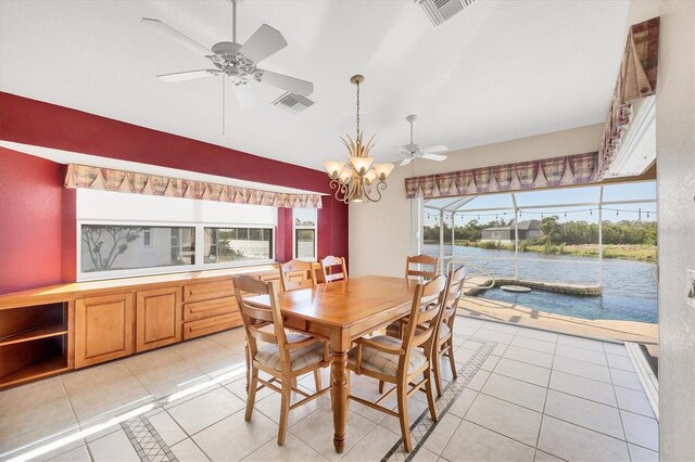 dining area with ceiling fan with notable chandelier, visible vents, a water view, and light tile patterned floors