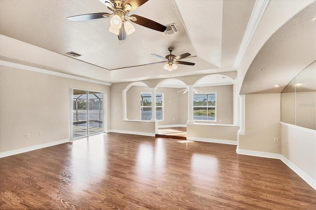 unfurnished room with a wealth of natural light, a tray ceiling, visible vents, and wood finished floors