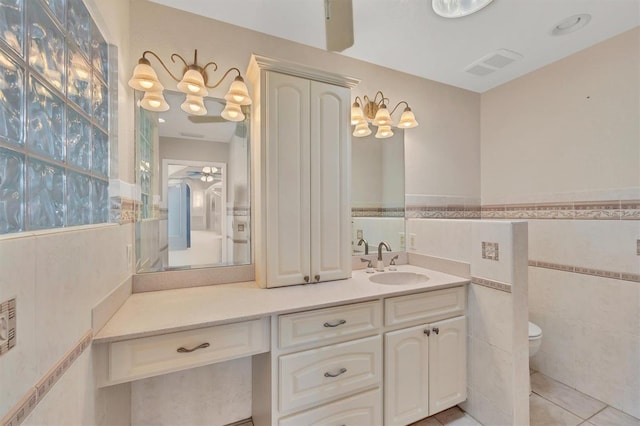 bathroom featuring tile walls, visible vents, toilet, vanity, and tile patterned floors