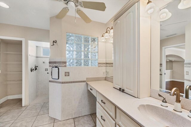 bathroom featuring a ceiling fan, vanity, tile walls, tiled shower, and tile patterned floors