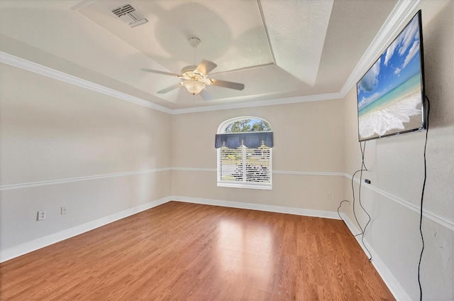 unfurnished room featuring a tray ceiling, visible vents, ceiling fan, wood finished floors, and baseboards