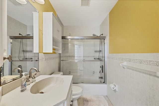 full bath with toilet, vanity, visible vents, and tile walls