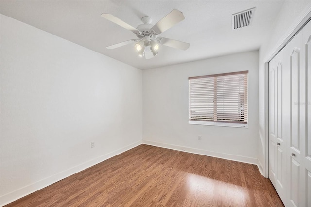 unfurnished bedroom with a closet, visible vents, baseboards, and wood finished floors