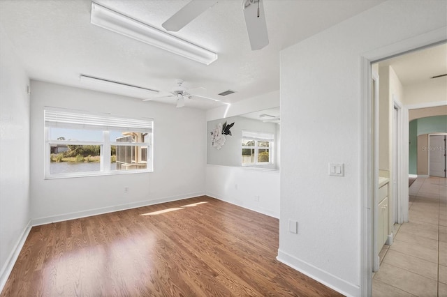 unfurnished room with ceiling fan, arched walkways, wood finished floors, visible vents, and baseboards