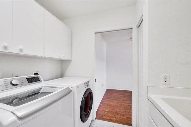 washroom featuring light wood-style floors, washer and dryer, and cabinet space