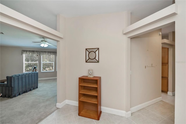 hall with light tile patterned flooring, baseboards, and light carpet