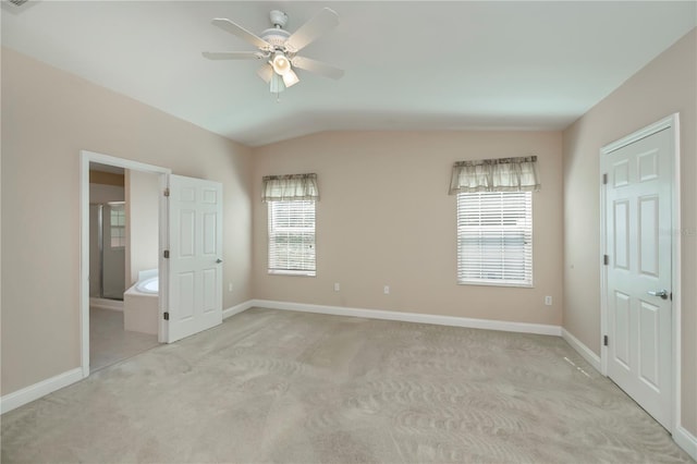 unfurnished bedroom featuring a ceiling fan, vaulted ceiling, light colored carpet, and baseboards