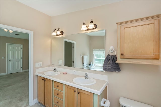 full bathroom with a sink, baseboards, toilet, and double vanity