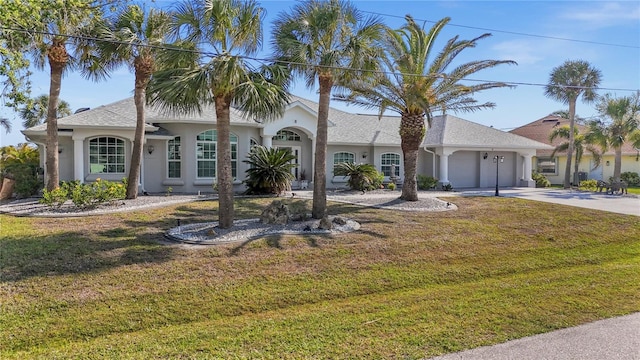 view of front of property with stucco siding, an attached garage, driveway, and a front lawn