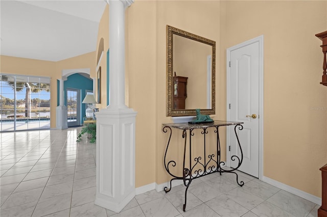 corridor featuring baseboards, arched walkways, marble finish floor, and ornate columns