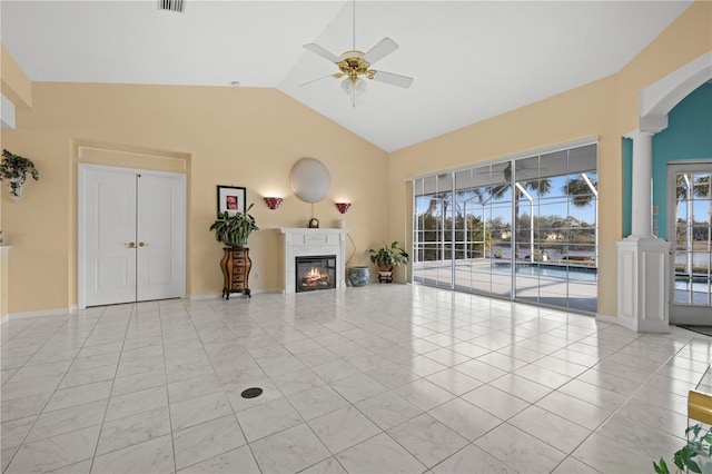 unfurnished living room with baseboards, lofted ceiling, decorative columns, a glass covered fireplace, and a ceiling fan