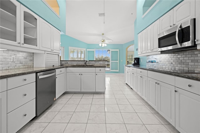 kitchen featuring glass insert cabinets, a peninsula, stainless steel appliances, a ceiling fan, and a sink