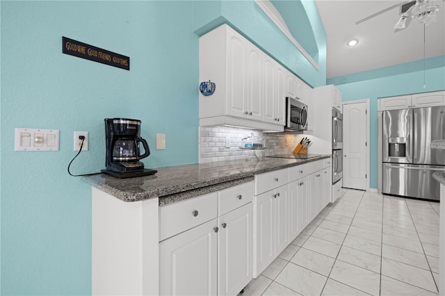 kitchen with decorative backsplash, dark stone counters, appliances with stainless steel finishes, and white cabinetry