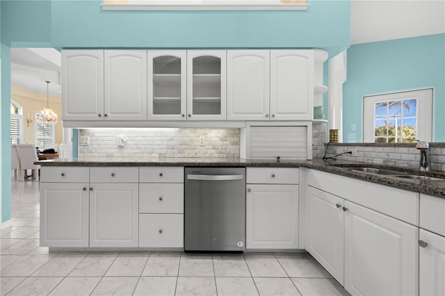 kitchen with a sink, tasteful backsplash, dark stone countertops, and white cabinetry