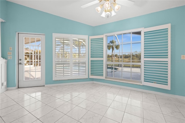 tiled empty room with a ceiling fan and baseboards