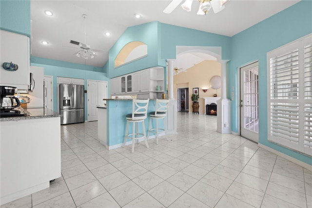 kitchen featuring stainless steel fridge, a peninsula, a breakfast bar area, white cabinets, and ceiling fan