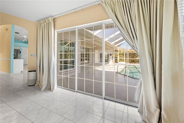 doorway featuring arched walkways and ceiling fan