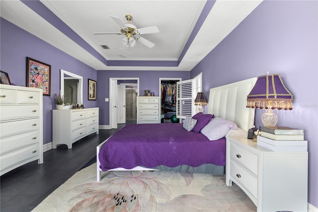 bedroom with a ceiling fan, baseboards, visible vents, crown molding, and a raised ceiling