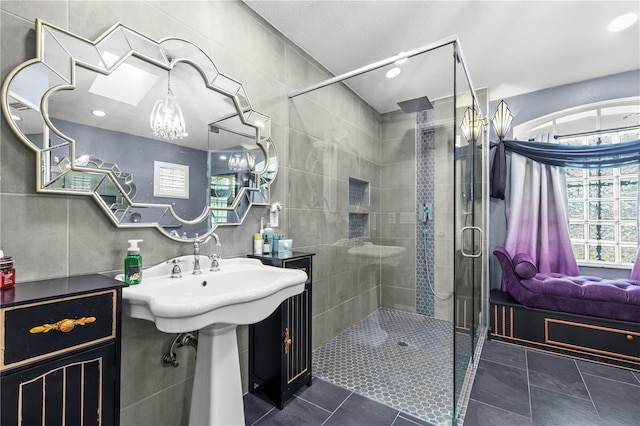 bathroom featuring tile patterned flooring, a shower stall, tile walls, and a sink