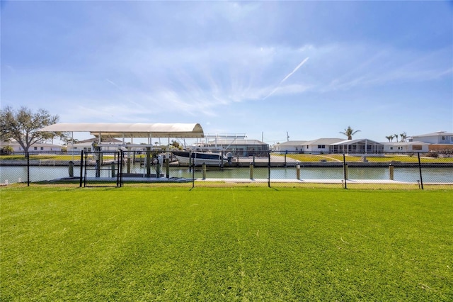 view of dock featuring a lawn, a water view, and fence