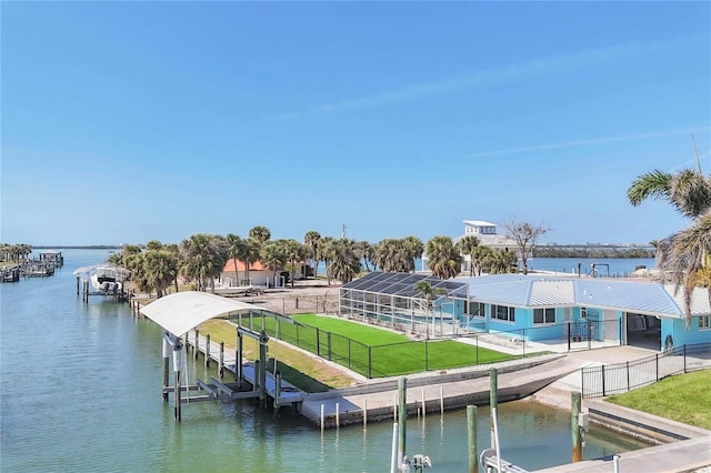 view of dock with a water view, boat lift, fence, and a lawn