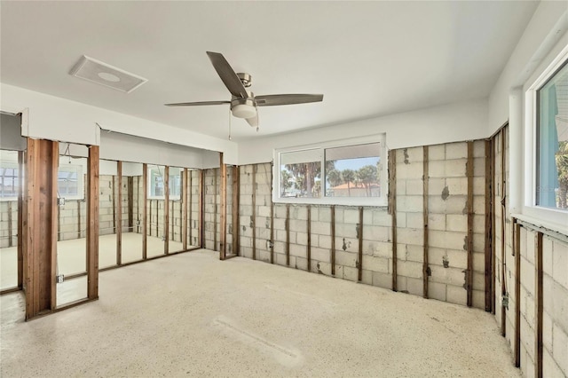 spare room with concrete block wall and ceiling fan