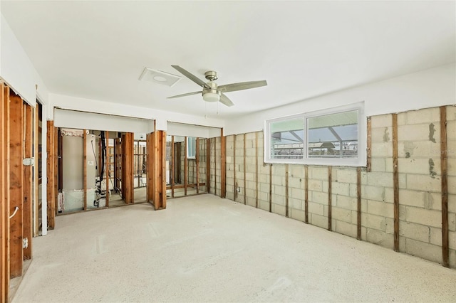 spare room featuring a ceiling fan and concrete block wall