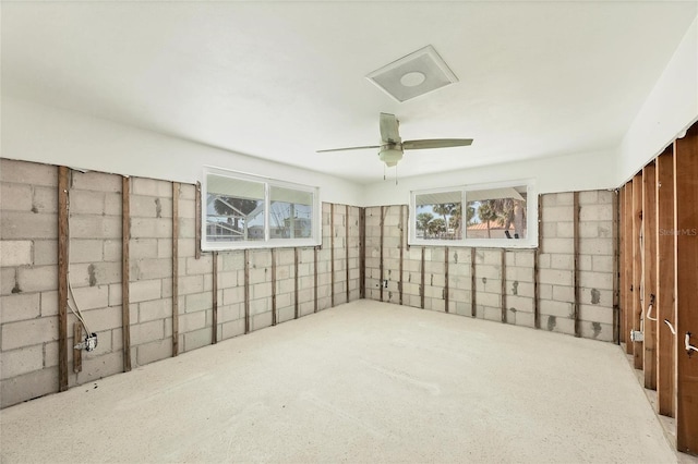 below grade area featuring a ceiling fan and concrete block wall