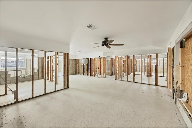 empty room featuring a healthy amount of sunlight, ceiling fan, visible vents, and speckled floor