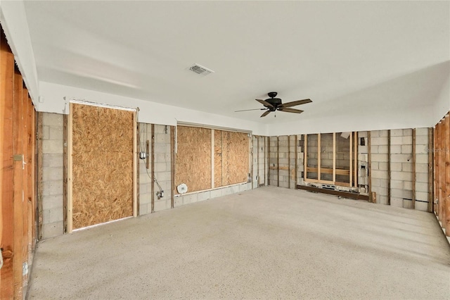 unfurnished room featuring a ceiling fan, concrete block wall, and visible vents