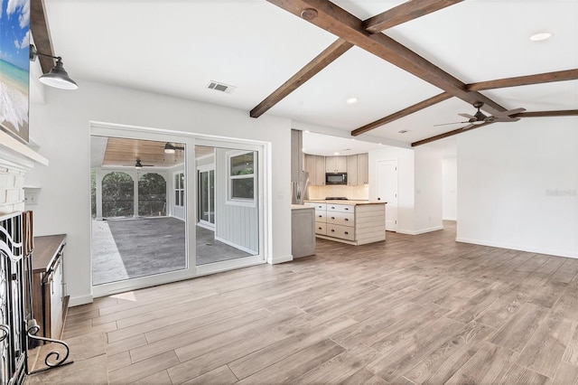 unfurnished living room featuring lofted ceiling with beams, light wood finished floors, visible vents, and baseboards