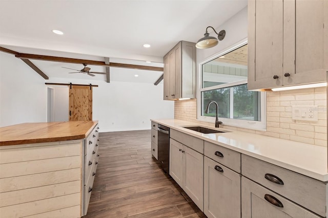 kitchen featuring dark wood-style floors, stainless steel dishwasher, a barn door, a sink, and butcher block countertops