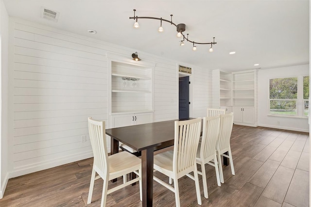 dining room featuring wooden walls, baseboards, visible vents, wood finished floors, and recessed lighting