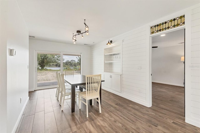 dining room with track lighting, wood finished floors, and baseboards