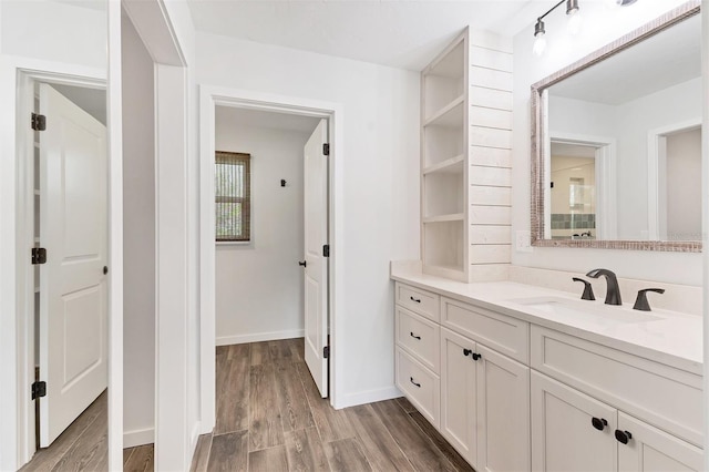 bathroom with wood finished floors, vanity, and baseboards