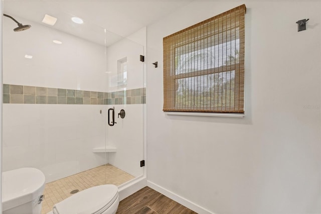 full bath featuring wood finished floors, a shower stall, toilet, and baseboards