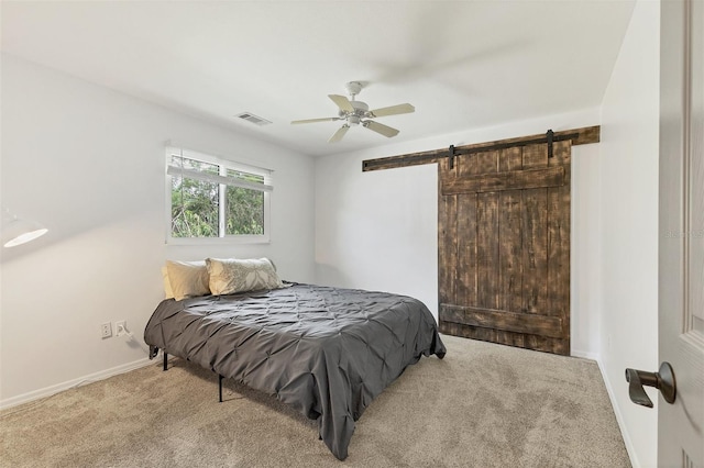 bedroom featuring a barn door, baseboards, visible vents, a ceiling fan, and carpet flooring