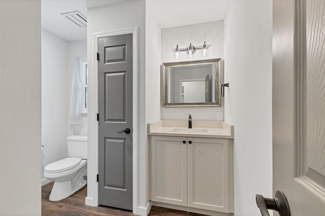 bathroom with baseboards, visible vents, toilet, wood finished floors, and vanity