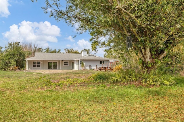 back of property featuring a lawn and a chimney