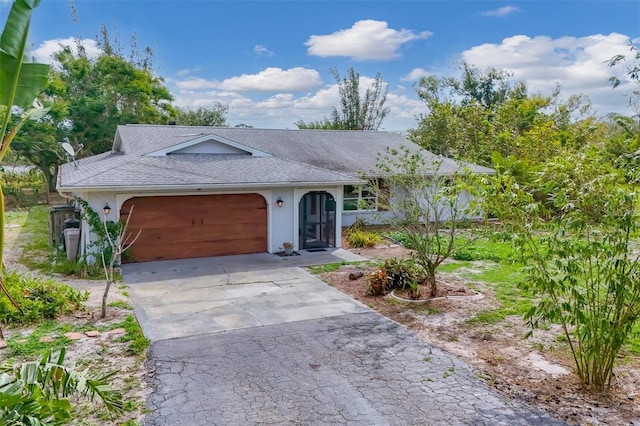 ranch-style house featuring a shingled roof, driveway, an attached garage, and stucco siding