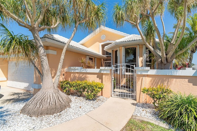 view of front of house featuring a fenced front yard, a gate, an attached garage, and stucco siding