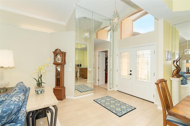 entrance foyer with ornamental molding, a notable chandelier, and french doors